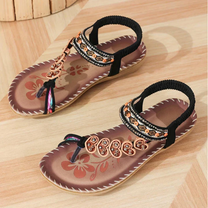 Pair of sandals with decorative straps on a wooden surface
