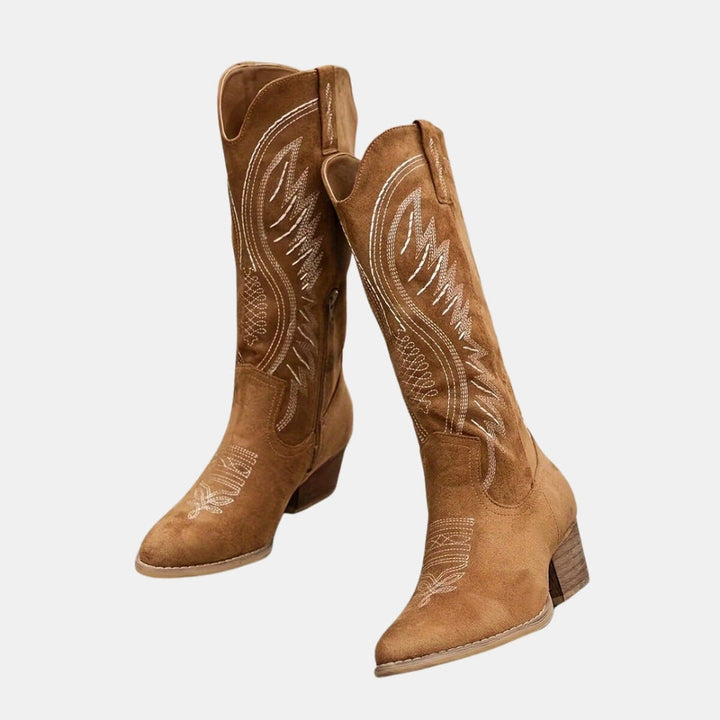 Pair of brown cowboy boots with white embroidery on a light gray background