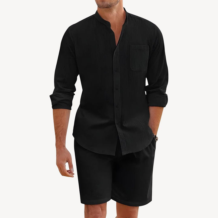 Man wearing a black long-sleeve shirt and black shorts on a white background