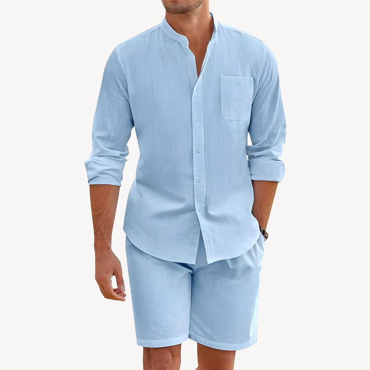 Man wearing a light blue button-up shirt and shorts set on a white background