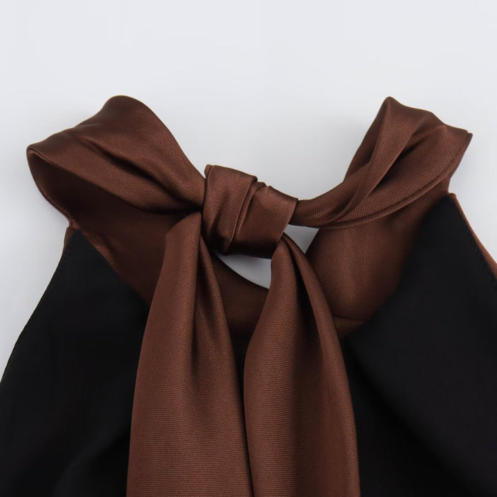 Brown bow tie on a black garment against a white background