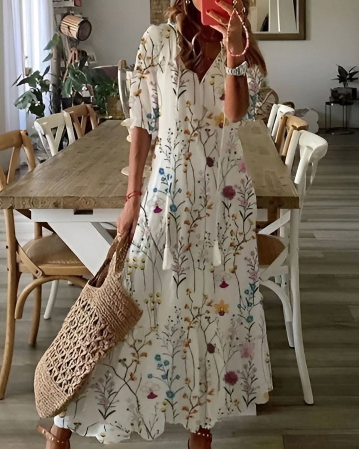 Woman in a floral dress holding a woven bag in a dining room.