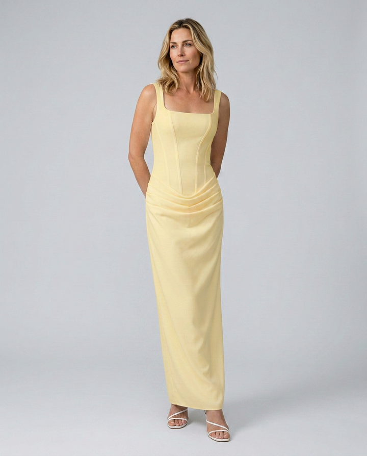 Woman wearing a light yellow dress against a plain background