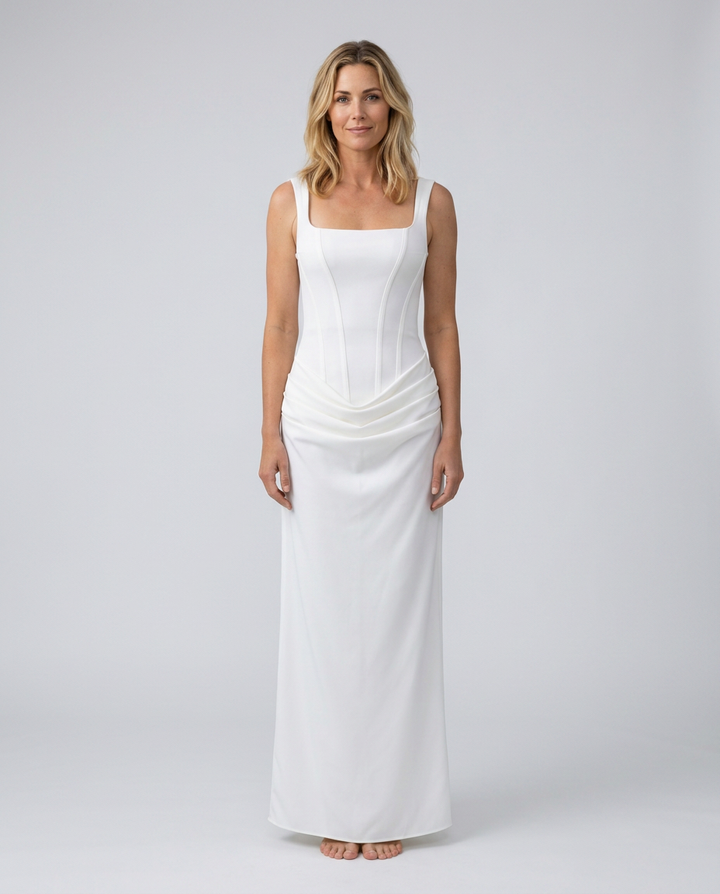 Woman wearing a white sleeveless dress against a plain background