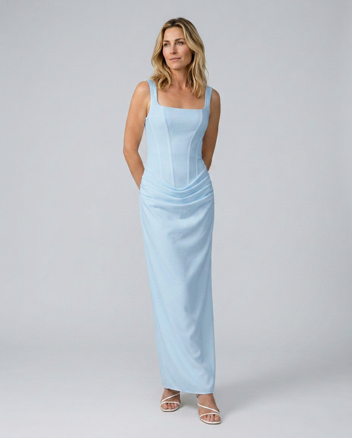 Woman wearing a light blue sleeveless dress against a plain background