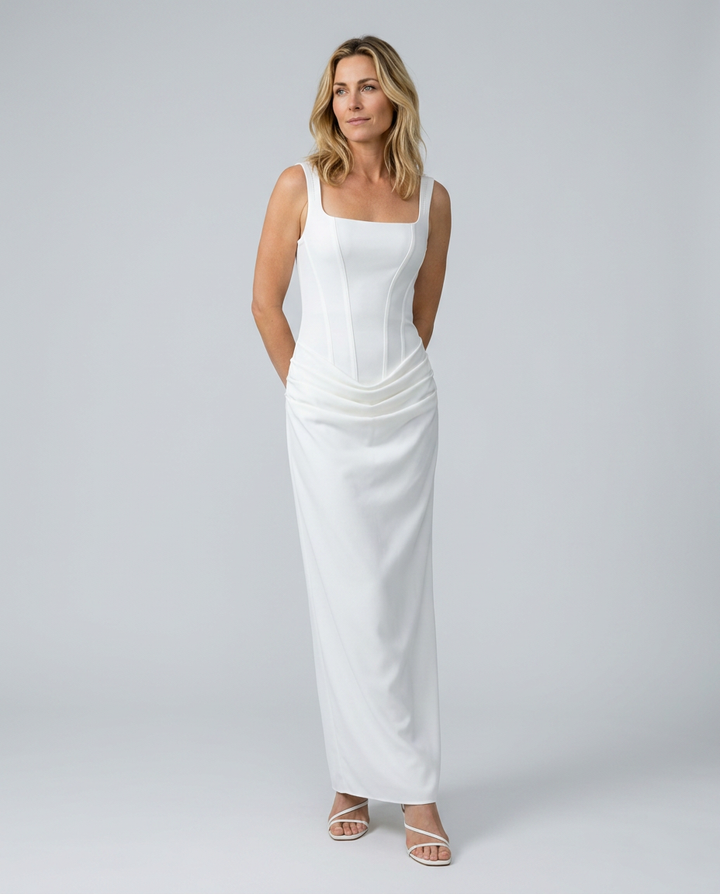 Woman wearing a white sleeveless dress against a plain background