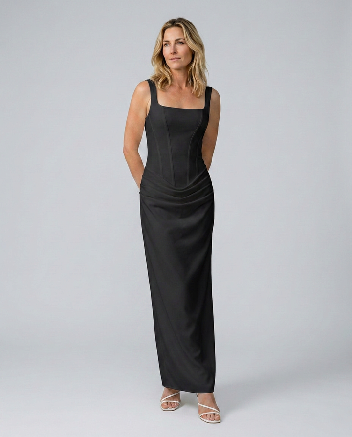 Woman wearing a black sleeveless dress against a gray background