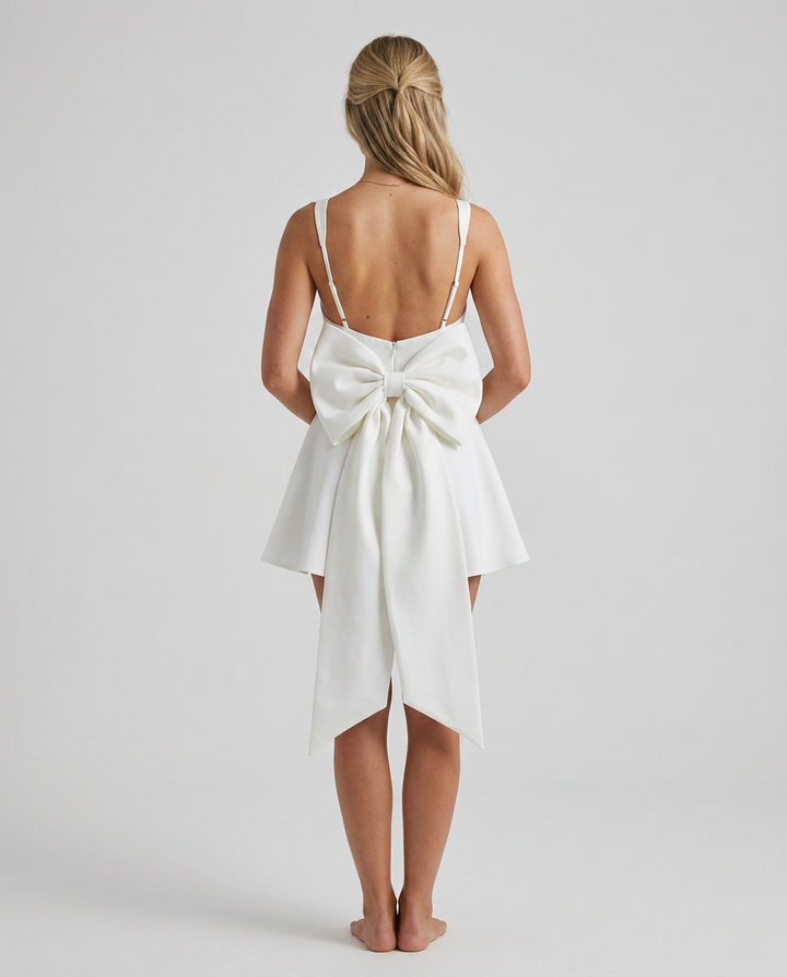 White dress with a large bow detail on a plain background