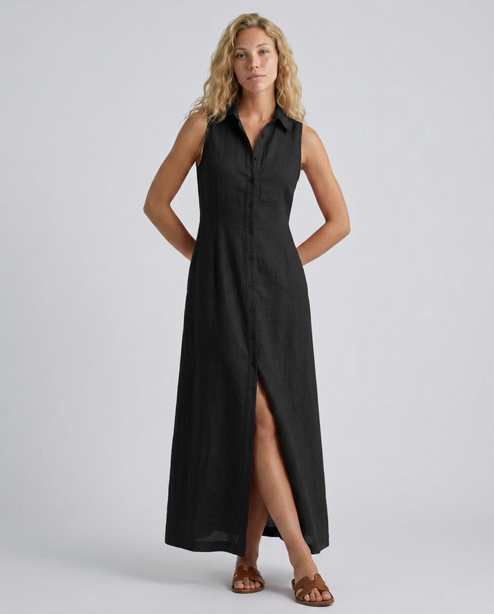 Woman wearing a black sleeveless dress with a slit on a plain background