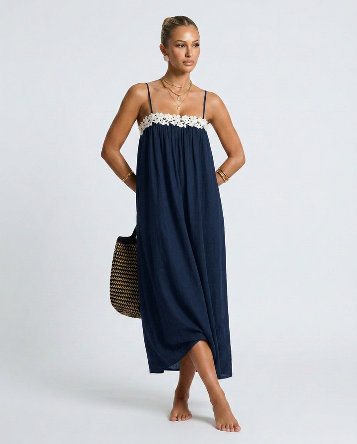 Woman wearing a navy blue dress with white floral details on a white background