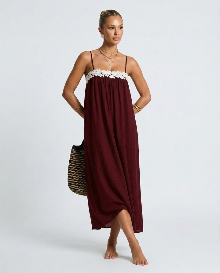 Woman wearing a burgundy dress with white lace trim on a plain background