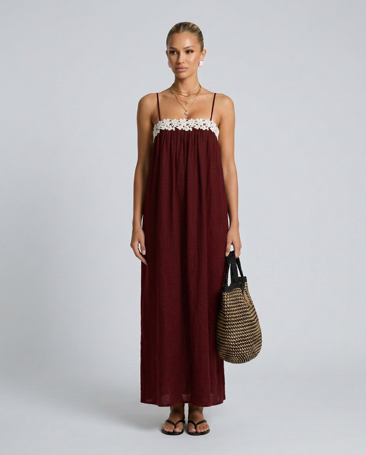 Woman wearing a burgundy dress with floral details on a gray background