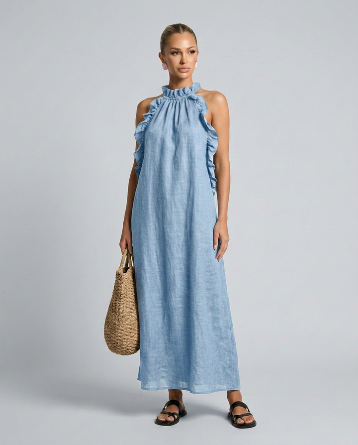 Woman wearing a blue dress holding a woven bag on a gray background