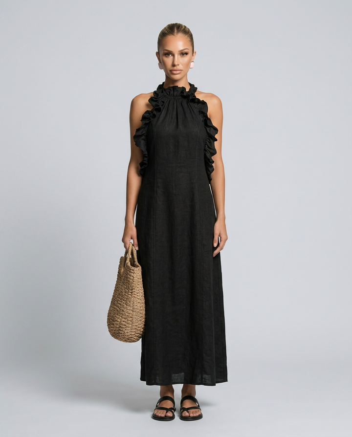 Woman wearing a black dress with ruffled shoulders against a gray background