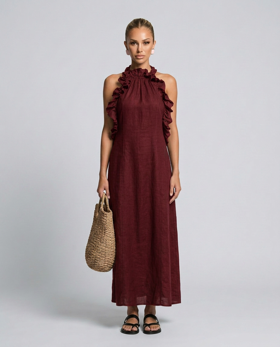 Woman wearing a burgundy dress with ruffled shoulders against a gray background