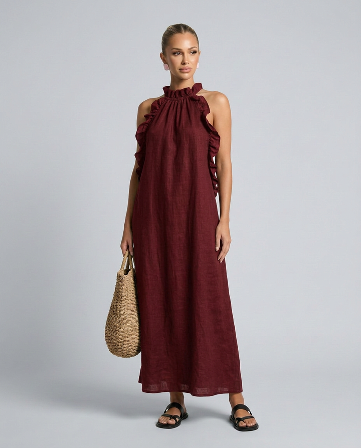 Woman wearing a burgundy dress with ruffled straps on a gray background