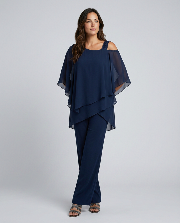 Woman wearing a navy blue outfit with a layered top and wide-leg pants on a white background