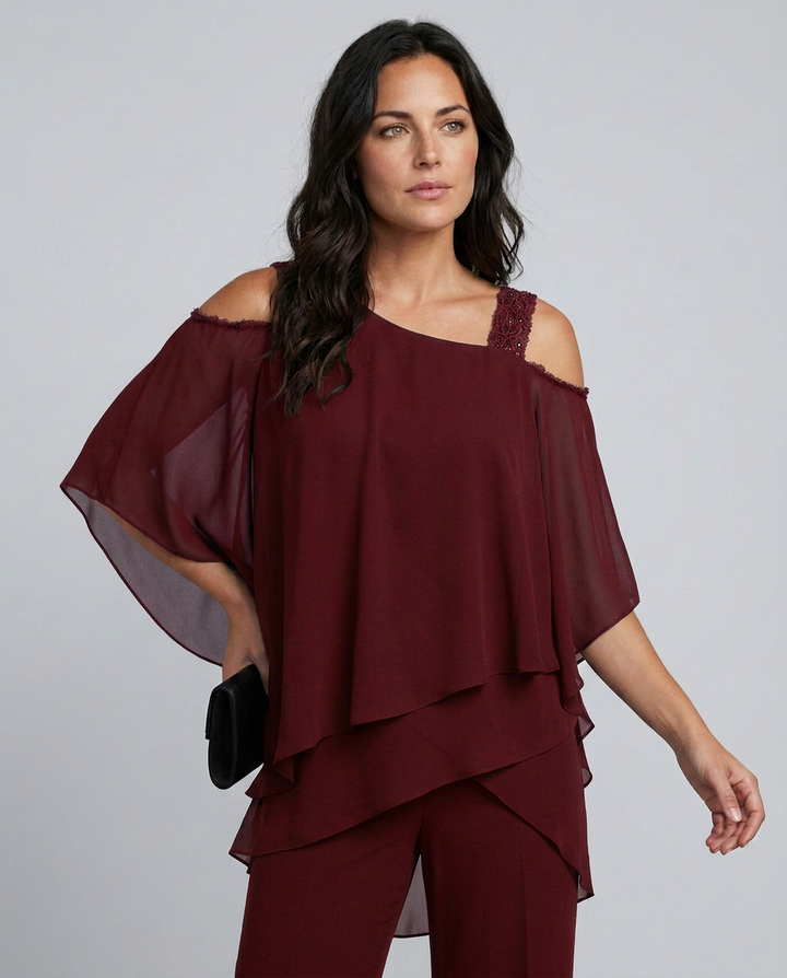 Woman wearing a burgundy off-shoulder top and pants on a gray background