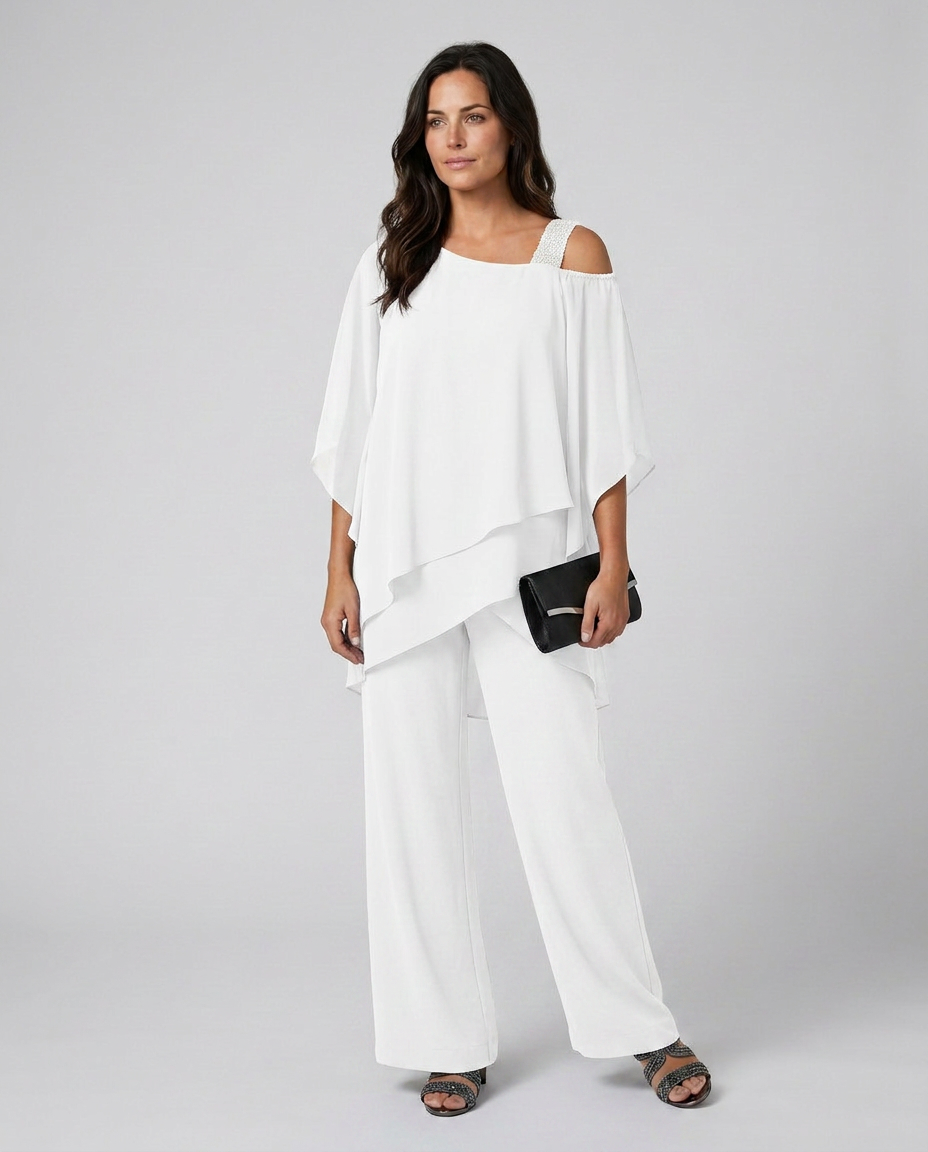 Woman wearing a white outfit with a black clutch against a gray background