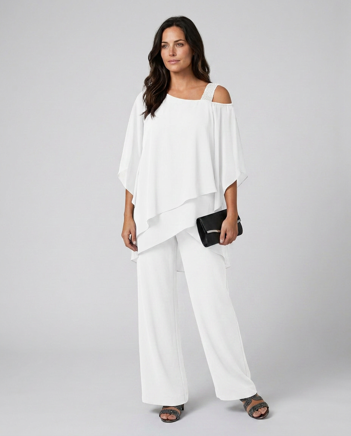 Woman wearing a white outfit with a black clutch against a gray background