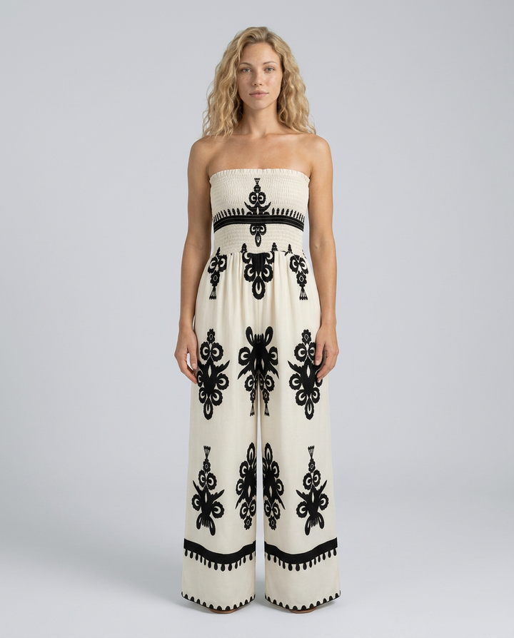 Woman wearing a strapless jumpsuit with black floral patterns on a plain background