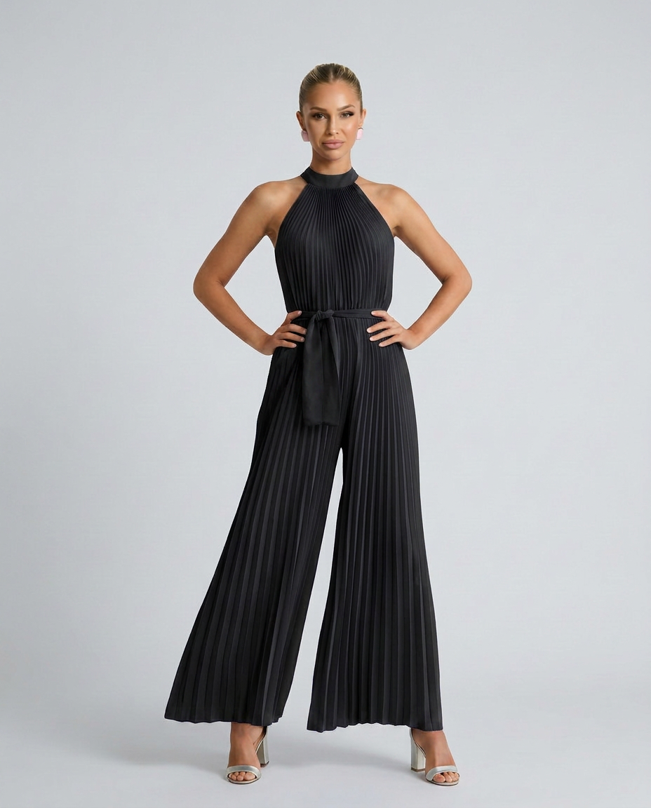 Woman wearing a black pleated jumpsuit on a gray background