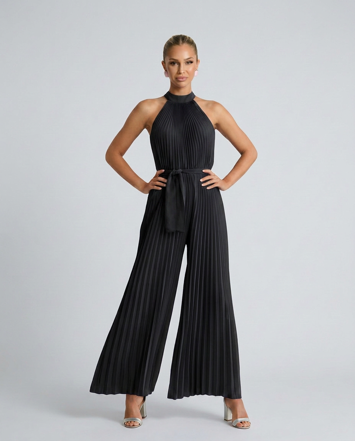 Woman wearing a black pleated jumpsuit on a gray background