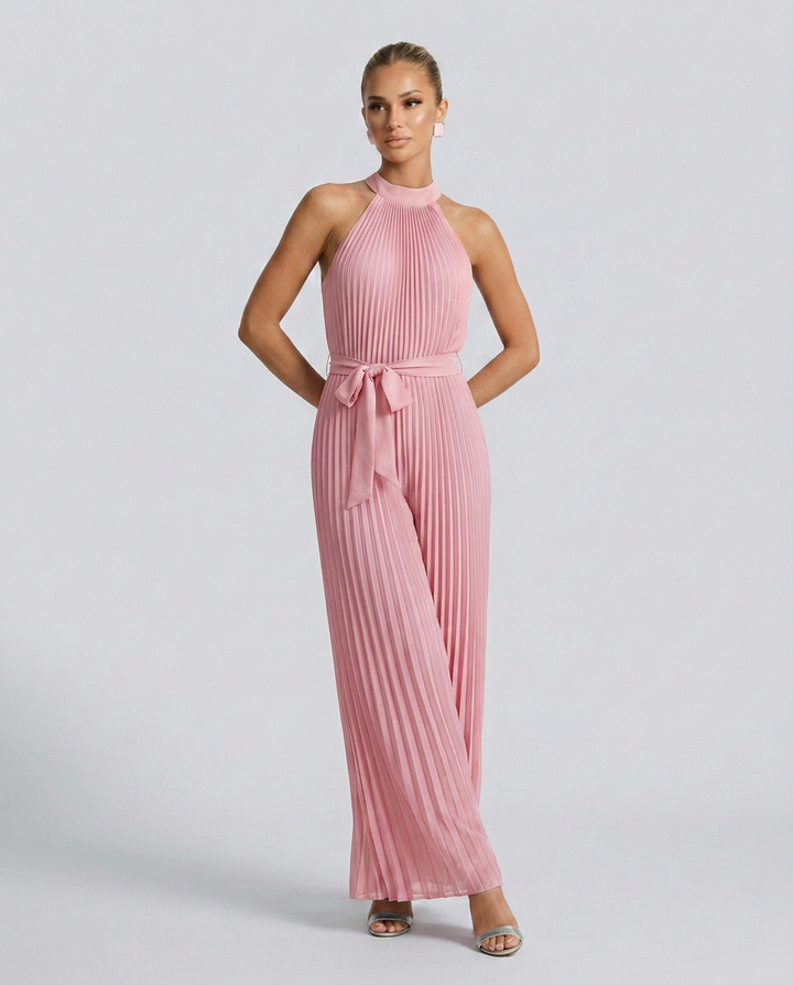 Woman wearing a pink pleated jumpsuit on a light gray background
