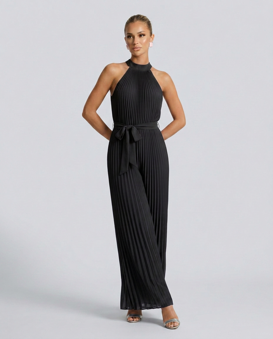 Woman wearing a black pleated jumpsuit on a light gray background