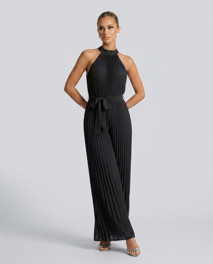 Woman wearing a black pleated jumpsuit on a light gray background