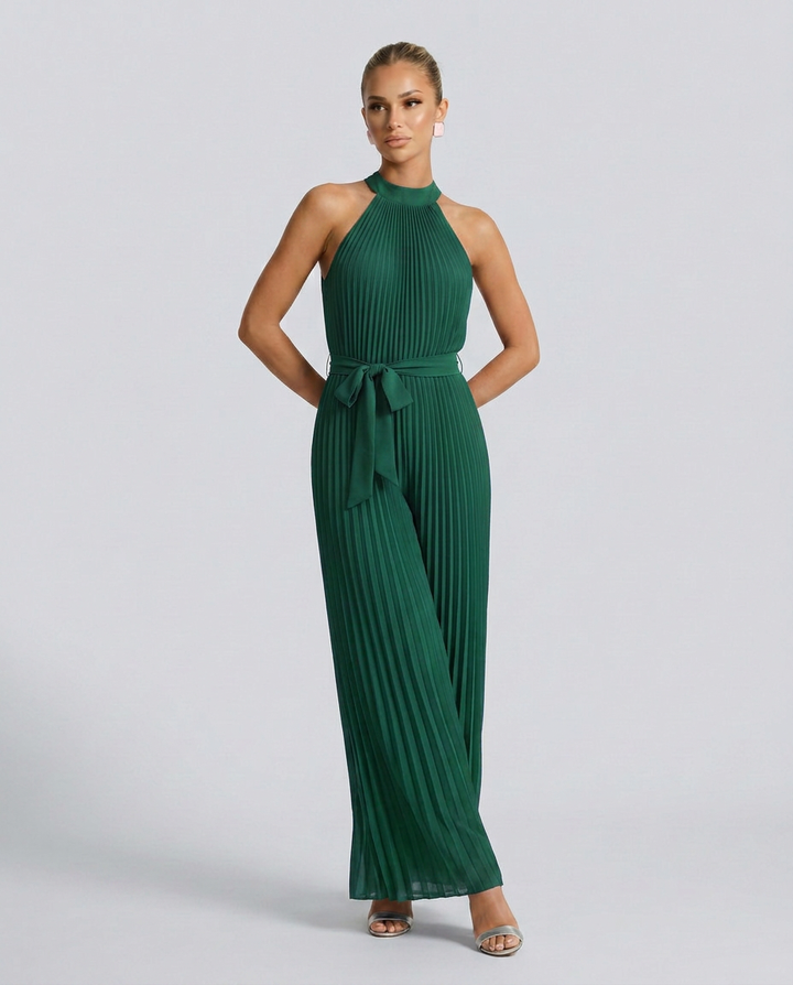 Woman wearing a green pleated jumpsuit on a light gray background