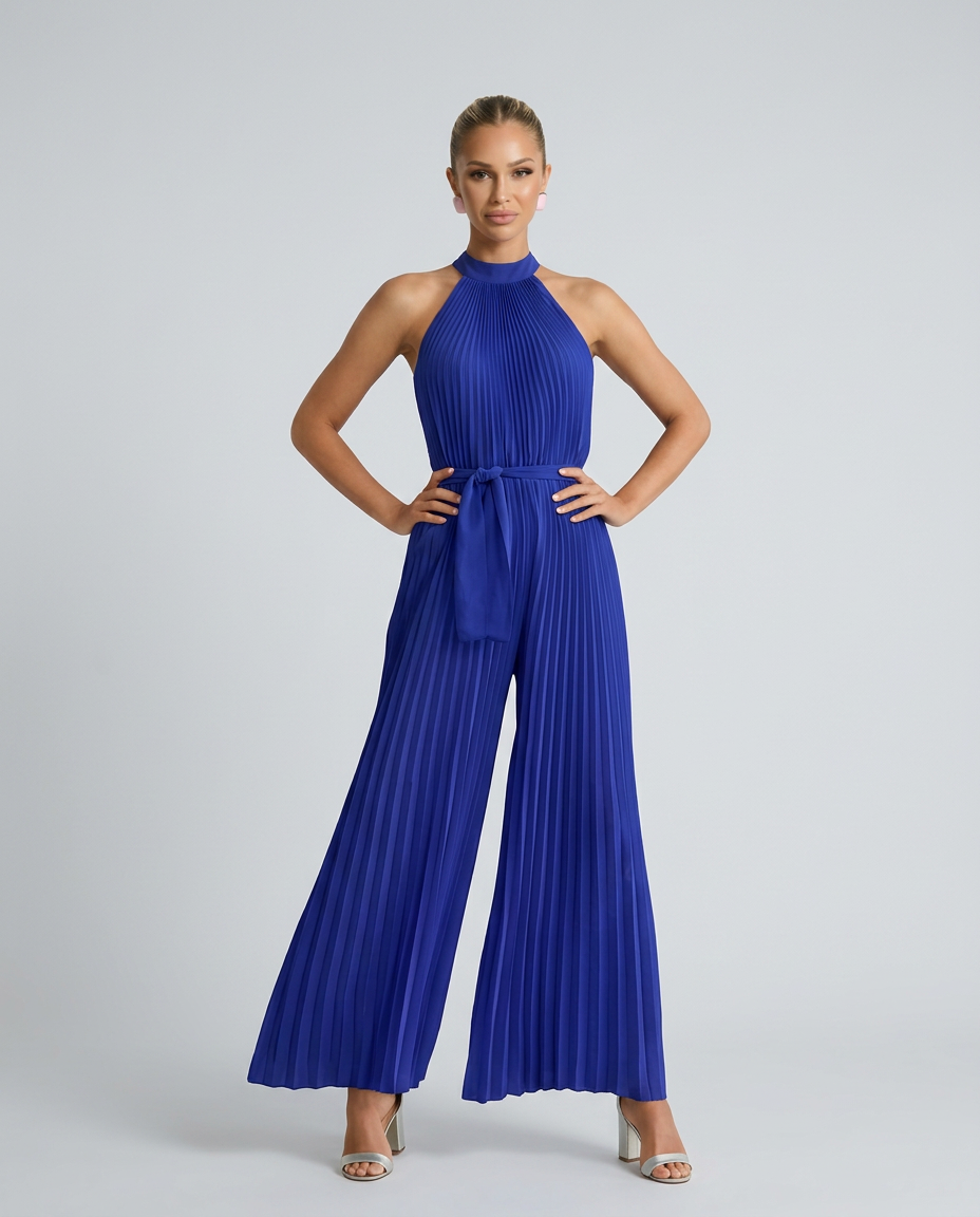 Woman wearing a blue pleated jumpsuit on a gray background