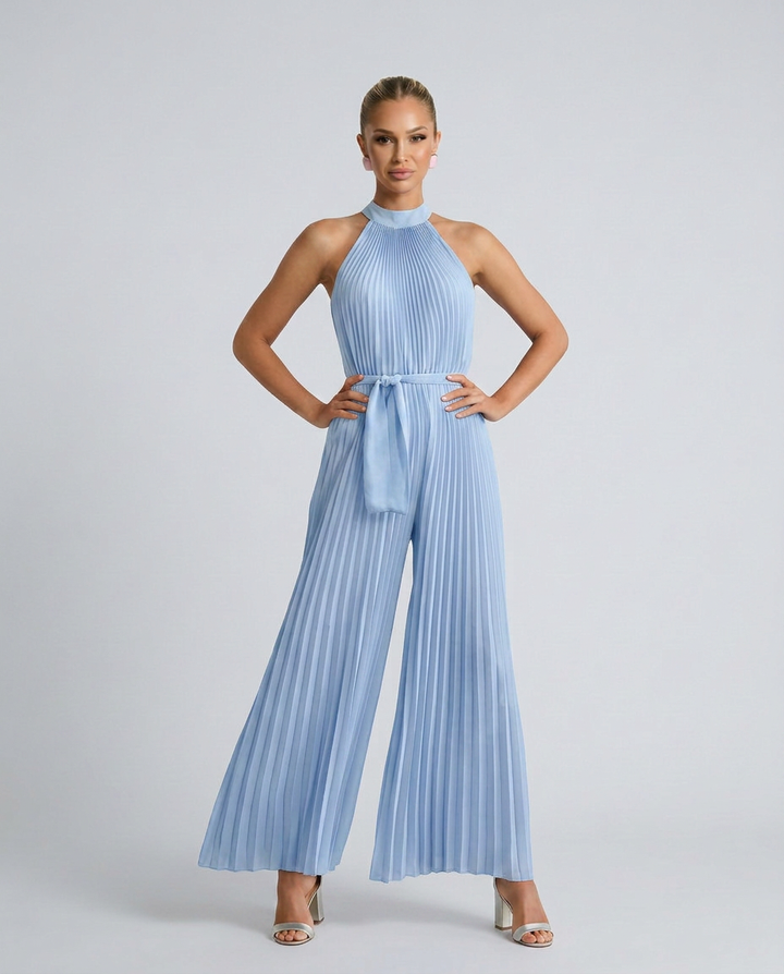 Woman wearing a light blue pleated jumpsuit on a plain background