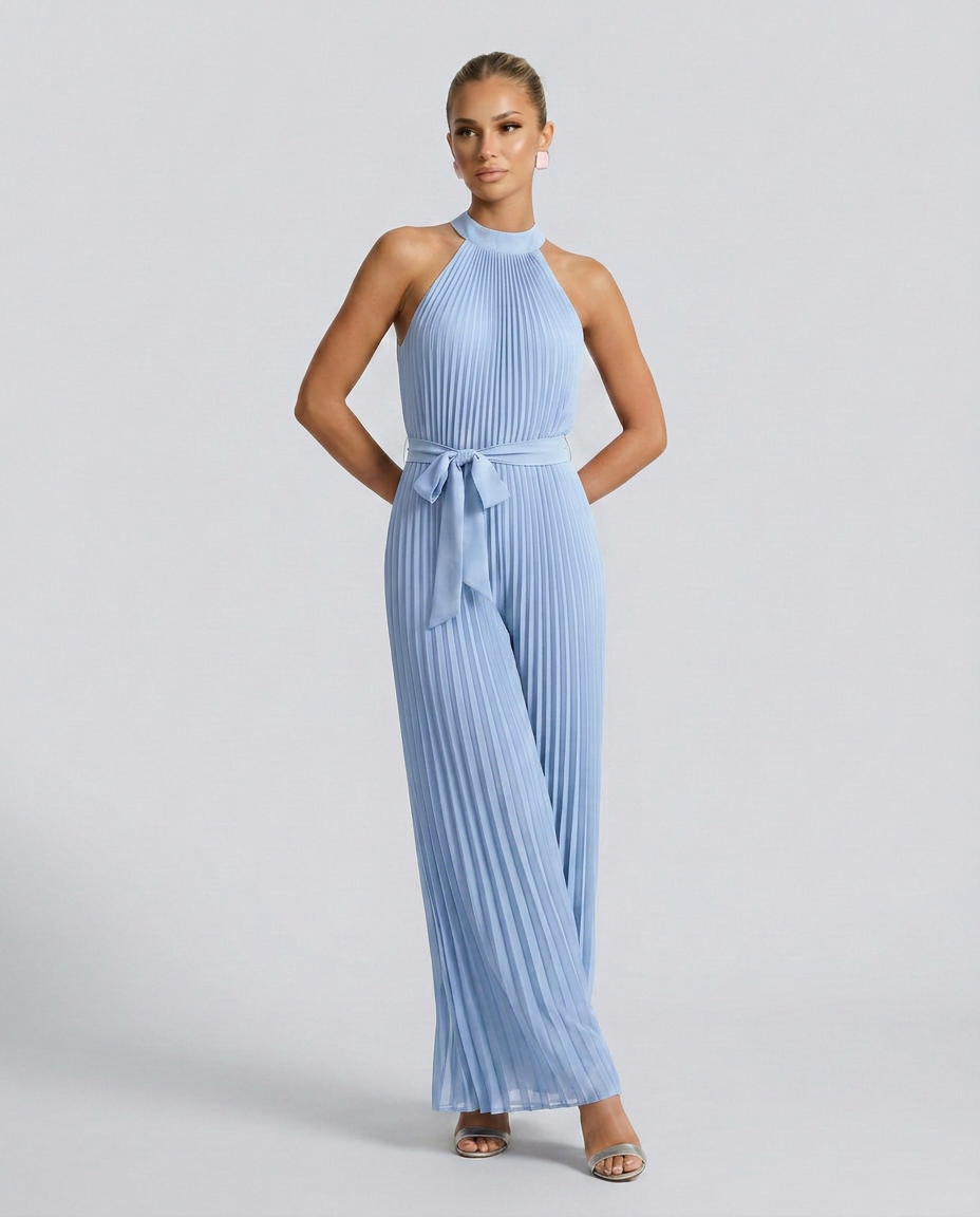 Woman wearing a light blue pleated jumpsuit on a gray background