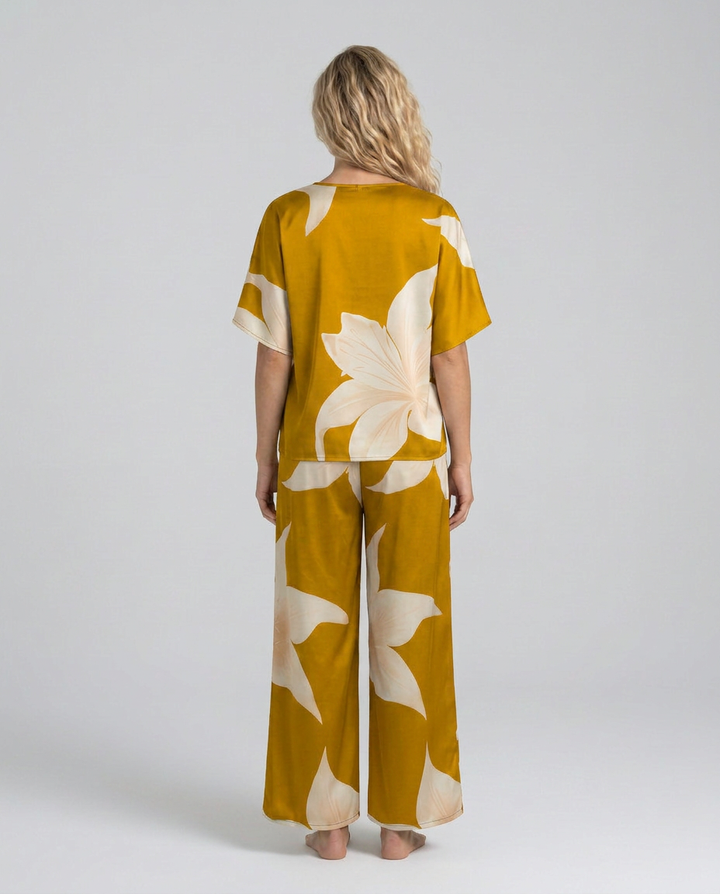 Woman wearing a mustard yellow outfit with floral patterns on a white background