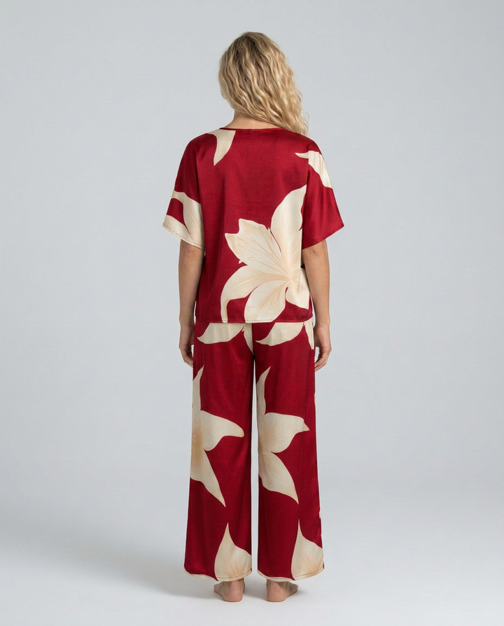 Woman wearing a red and beige floral jumpsuit on a plain background