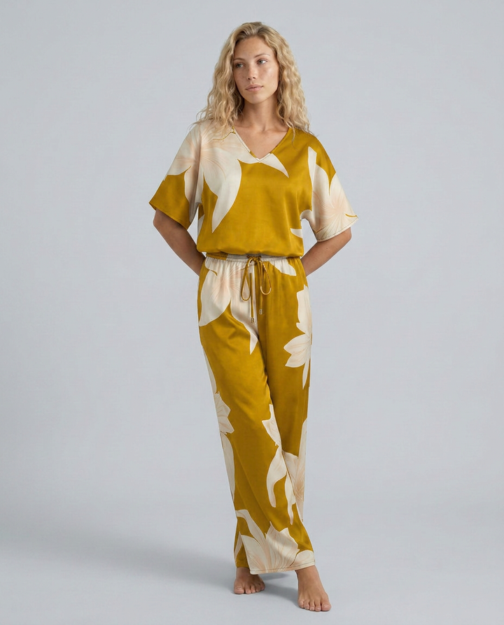 Woman wearing a mustard yellow and white floral pajama set on a gray background