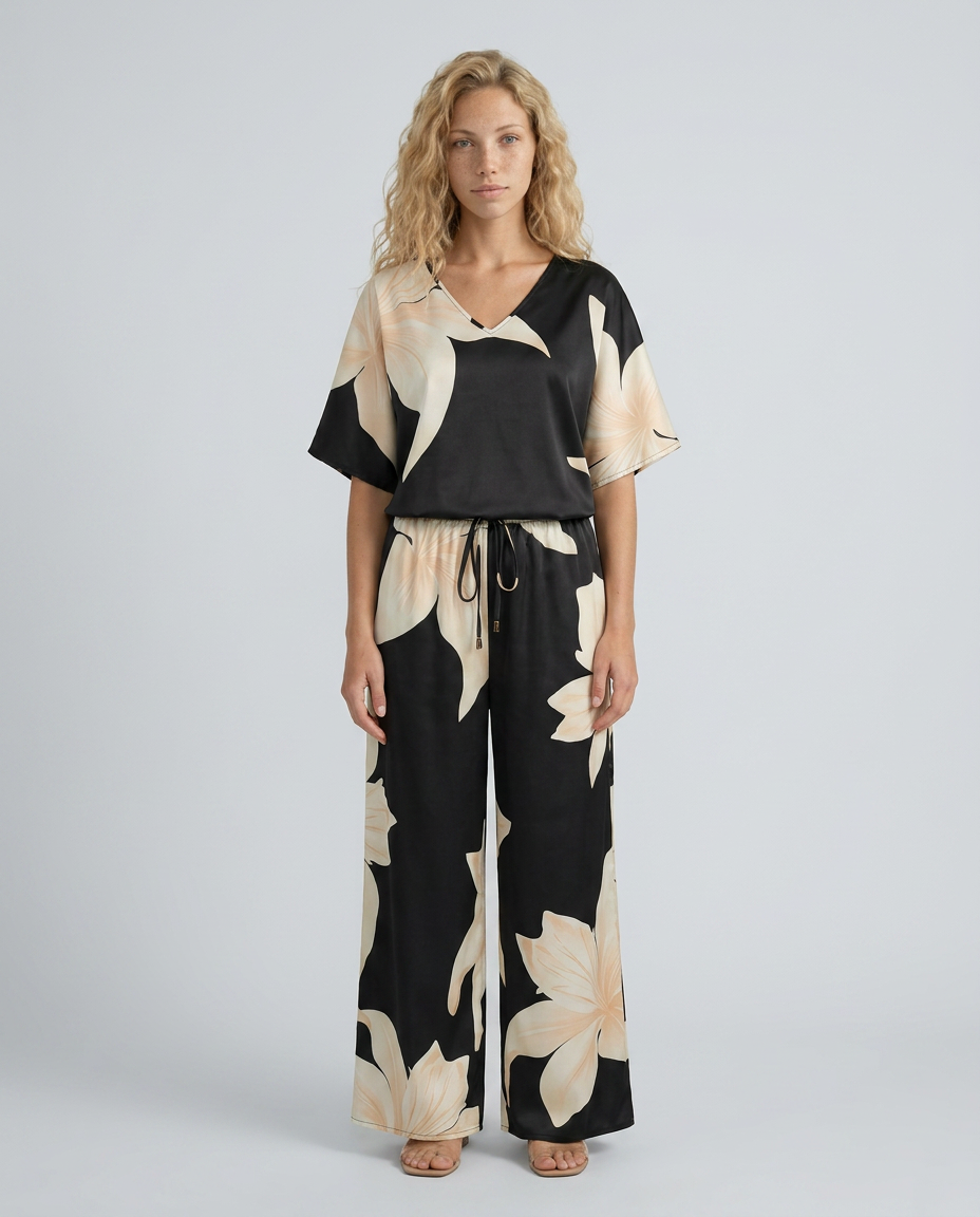 Woman wearing a black and beige floral jumpsuit on a gray background