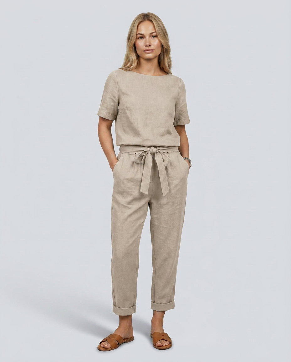 Woman wearing a beige outfit with a tie-waist pants and shirt on a plain background