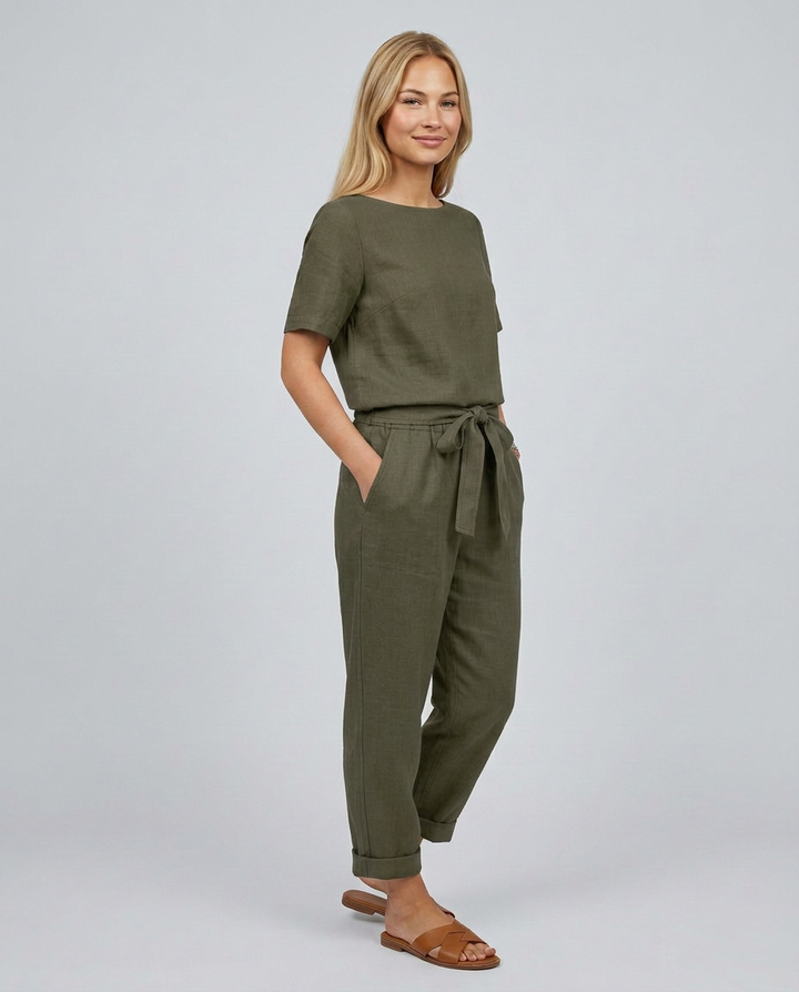 Woman wearing an olive green jumpsuit on a plain background