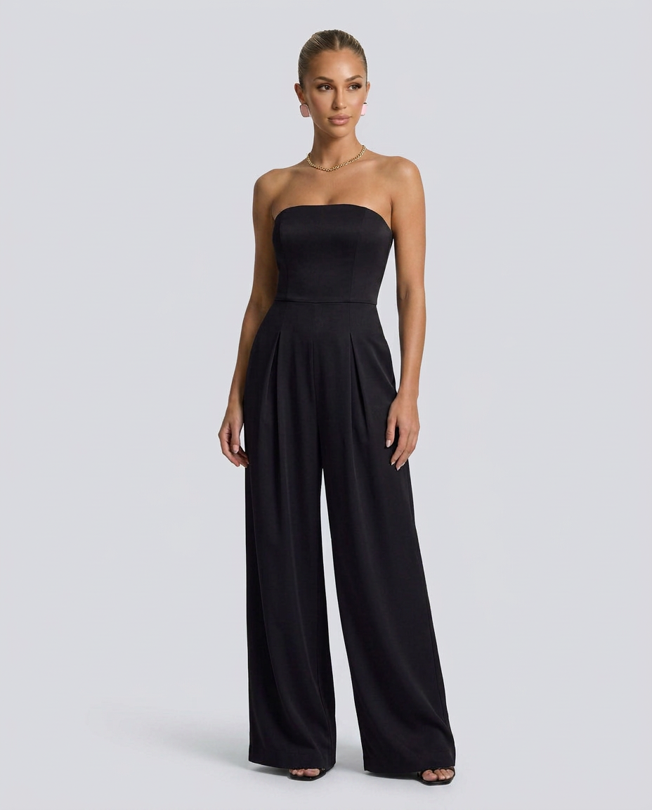 Woman wearing a black strapless jumpsuit on a light gray background