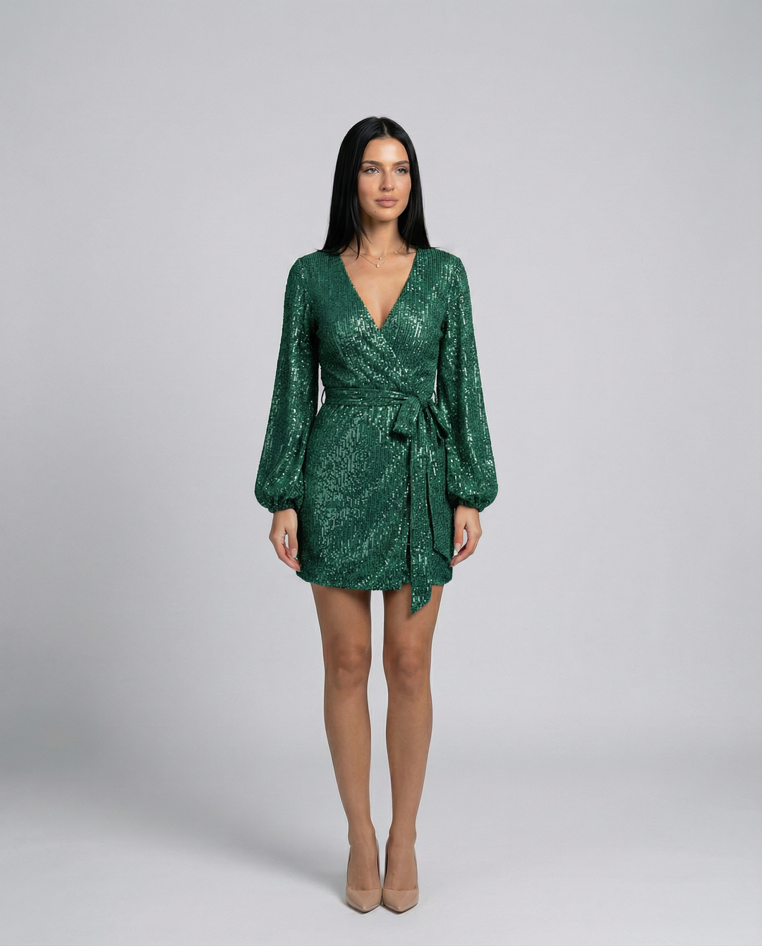 Woman wearing a green sequin dress on a gray background