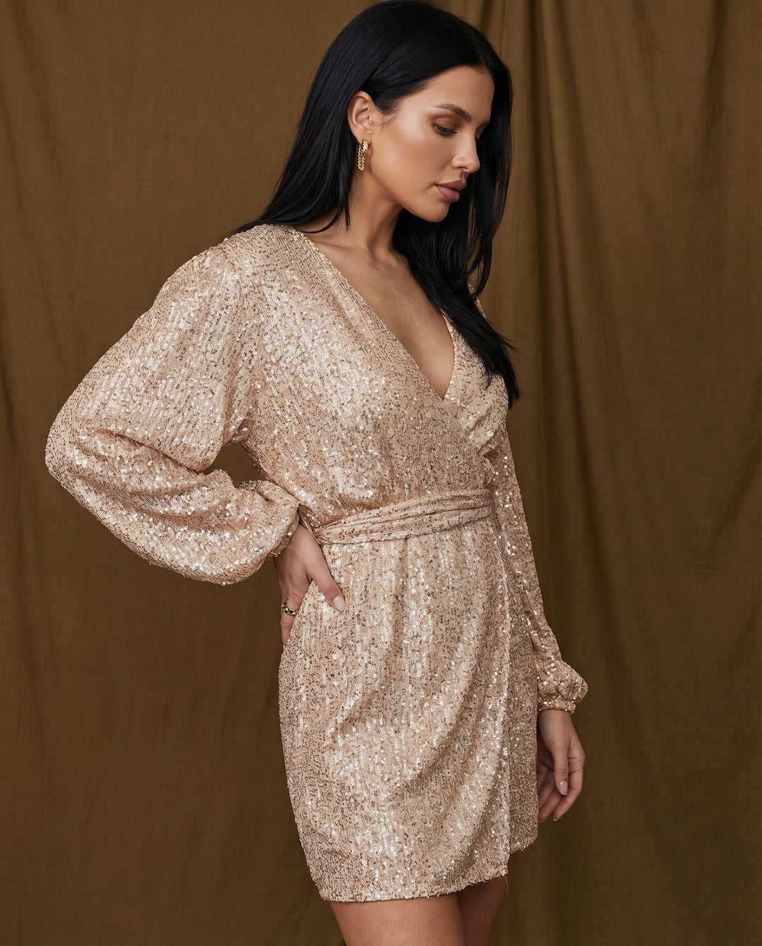 Woman wearing a sparkly gold dress against a brown background