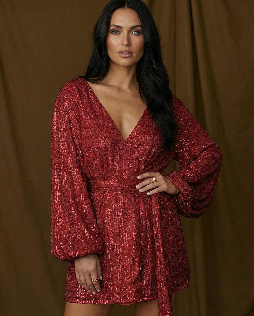 Woman wearing a red sequin dress against a brown curtain background