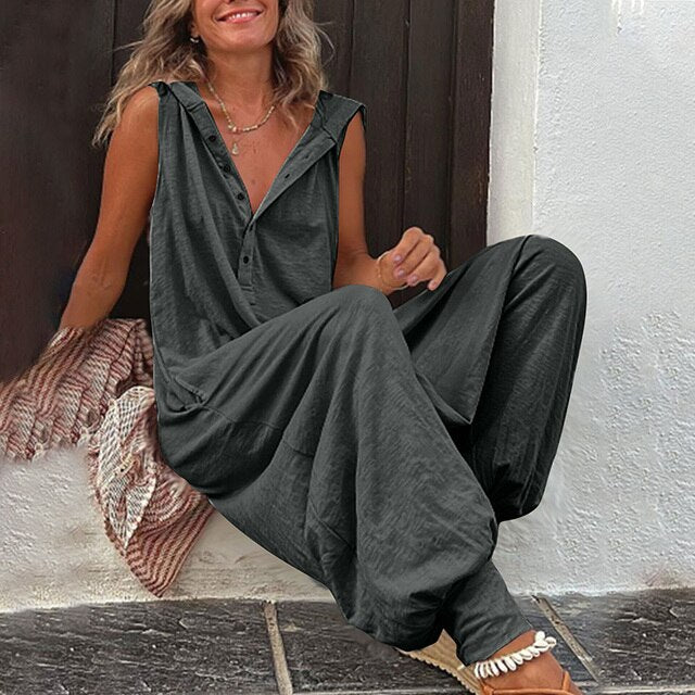 Woman wearing a dark green sleeveless jumpsuit sitting on a stone step.
