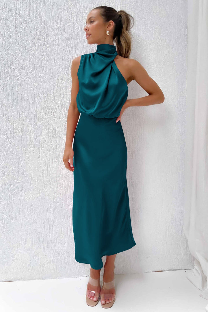 Woman wearing a teal one-shoulder dress against a white background