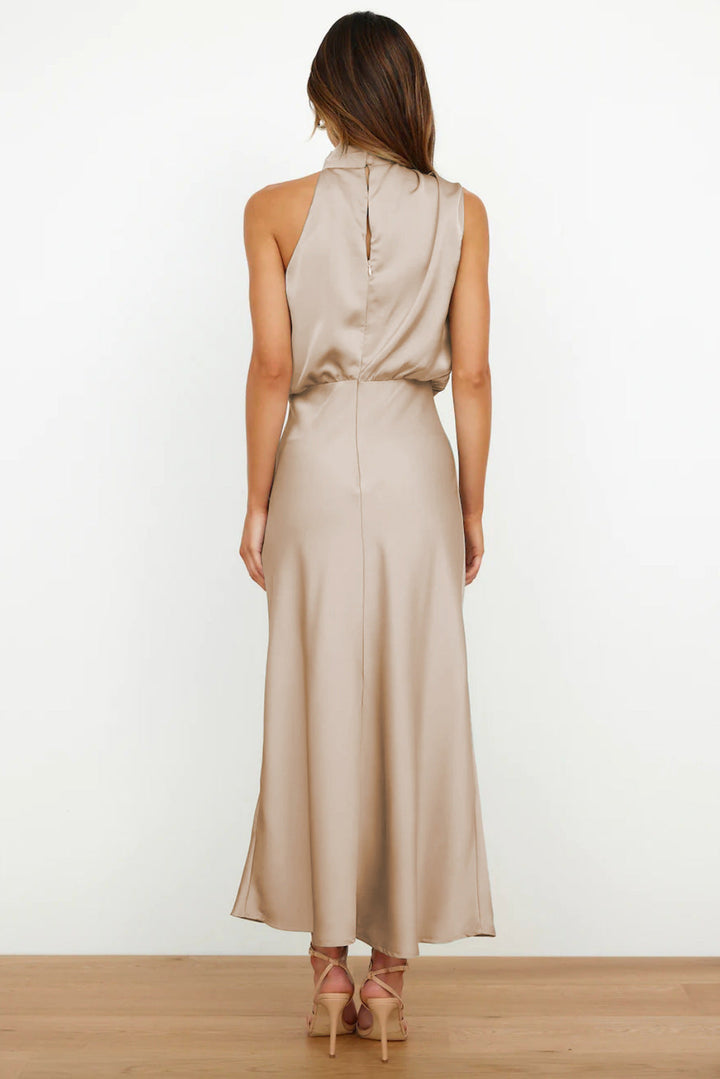 Woman wearing a beige halter neck dress on a white background