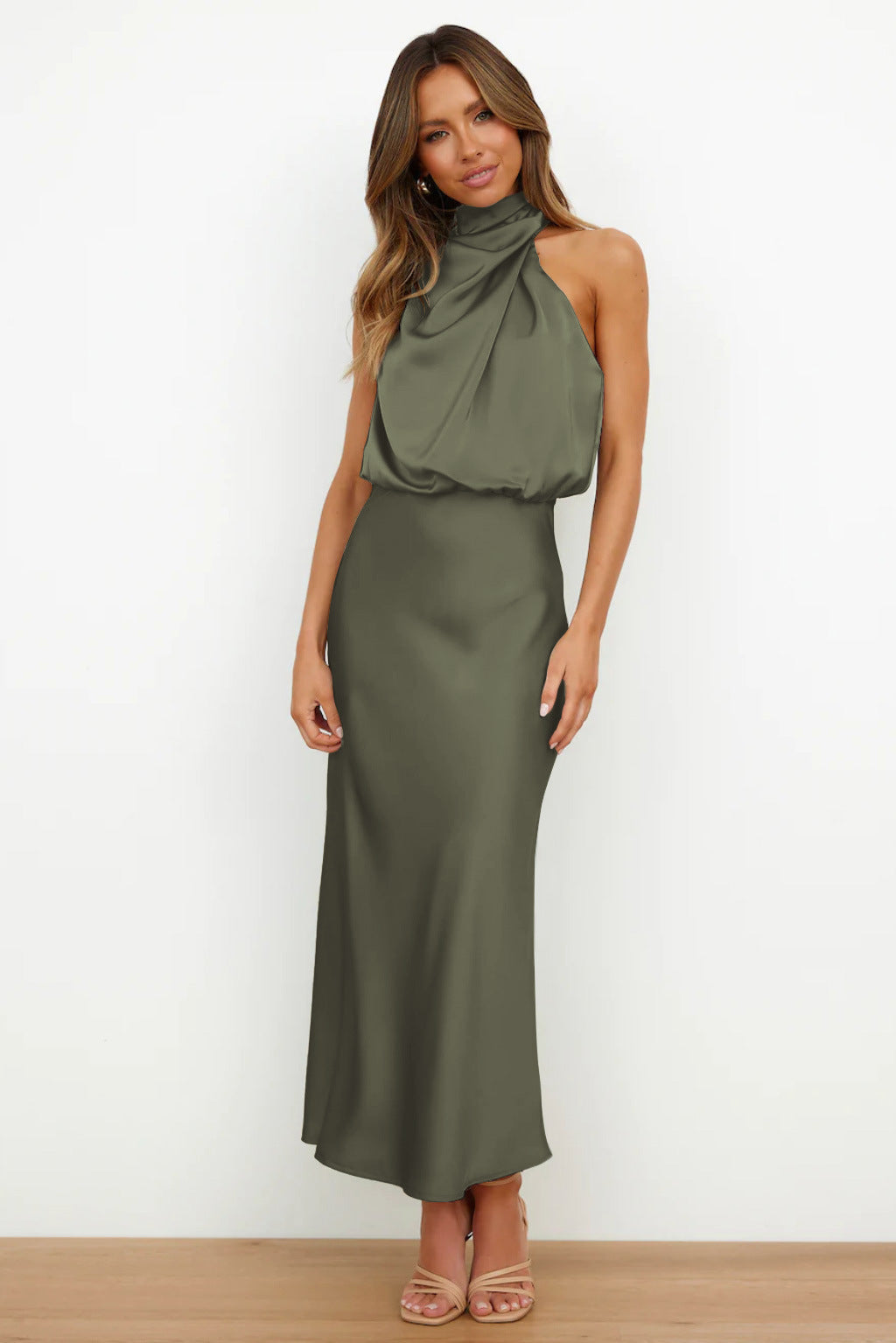 Woman wearing an olive green halter neck dress on a white background