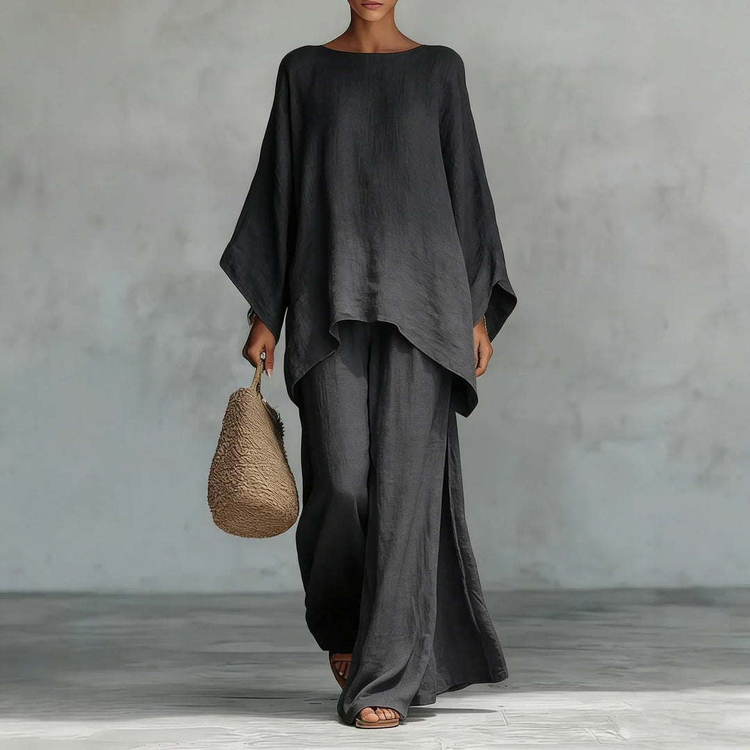 Person wearing a black outfit holding a woven bag against a gray background