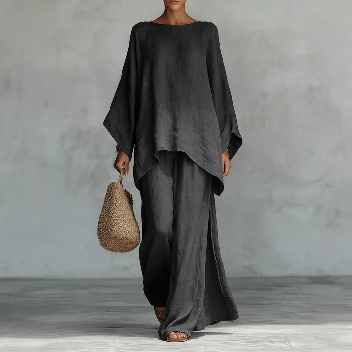 Person wearing a black outfit holding a woven bag against a gray background